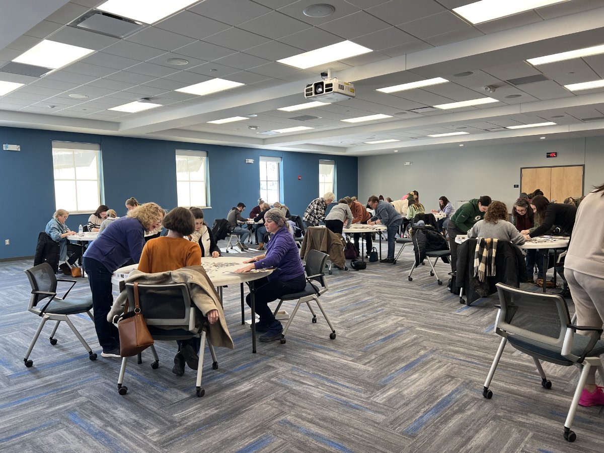group of people sitting at tables doing a puzzle